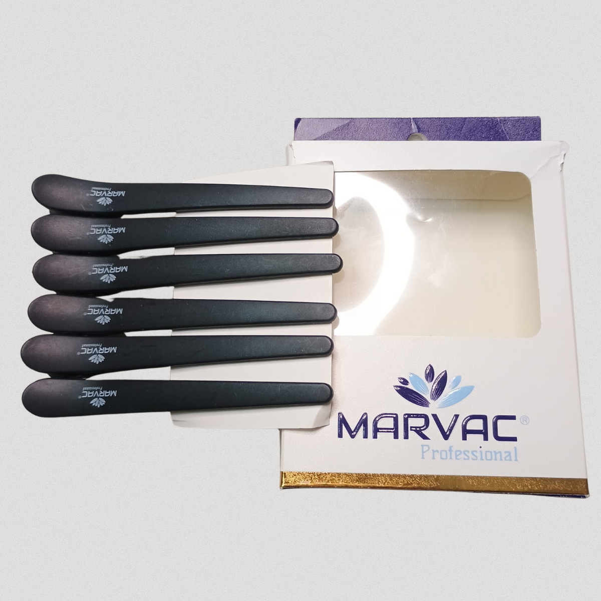 Carbon fiber hair section clips by Marvac placed on branded box for professional salon use